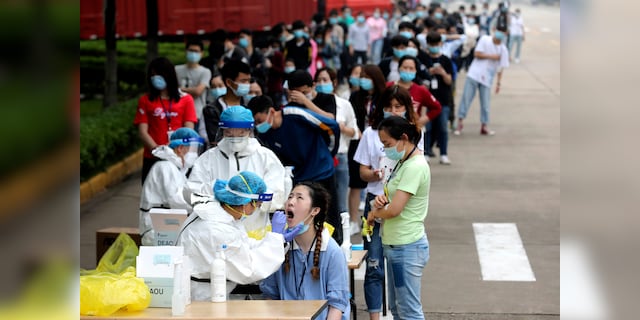 People line up to receive medical workers to take samples for a coronavirus test at a large factory in Wuhan, central China's Hubei Province, on May 15.